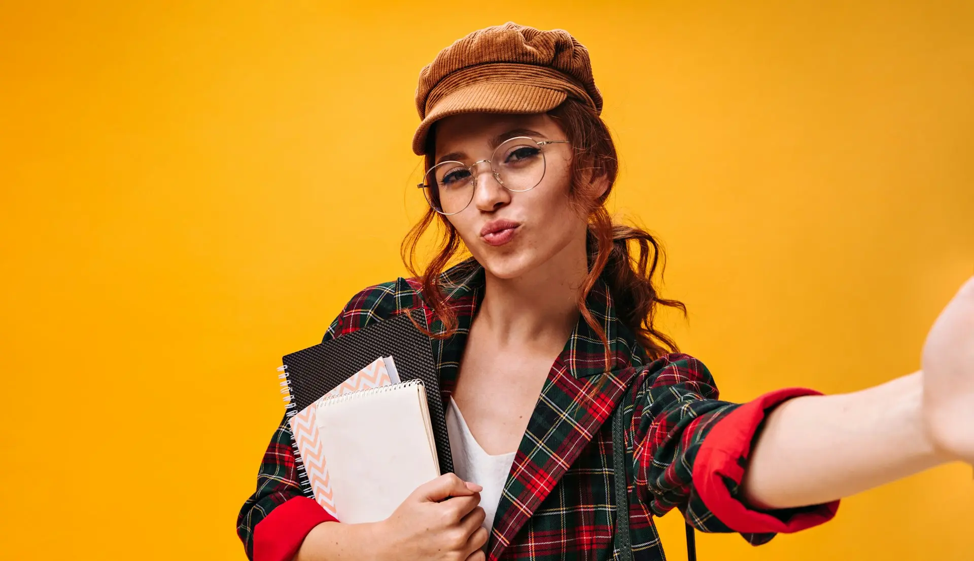 a woman with glasses and a hat holding a binder